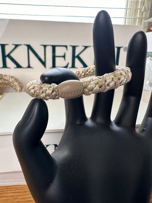 KKNEKKI Ivory Beige Glitter Stripe hair elastic on a hand model in front of a branded KKNEKKI box 