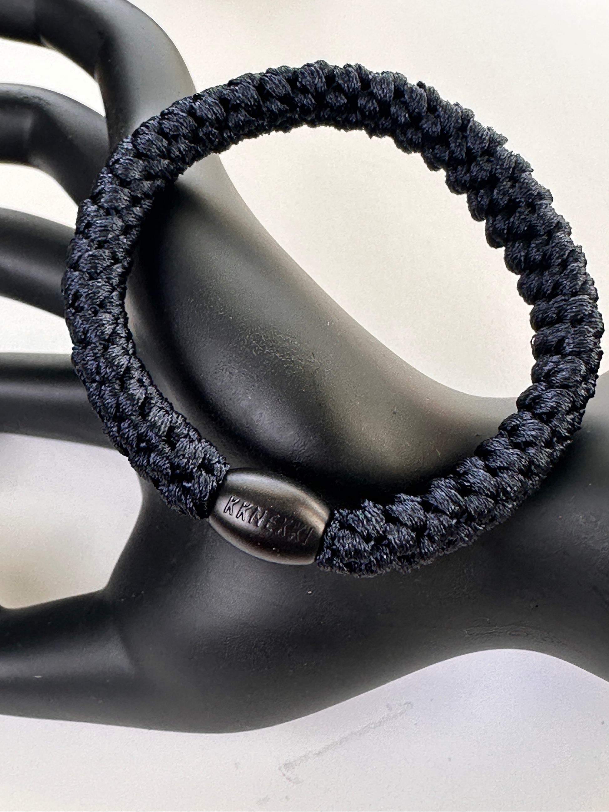 IKKNEKKI Old Navy hair tie on a black hand model with a white background