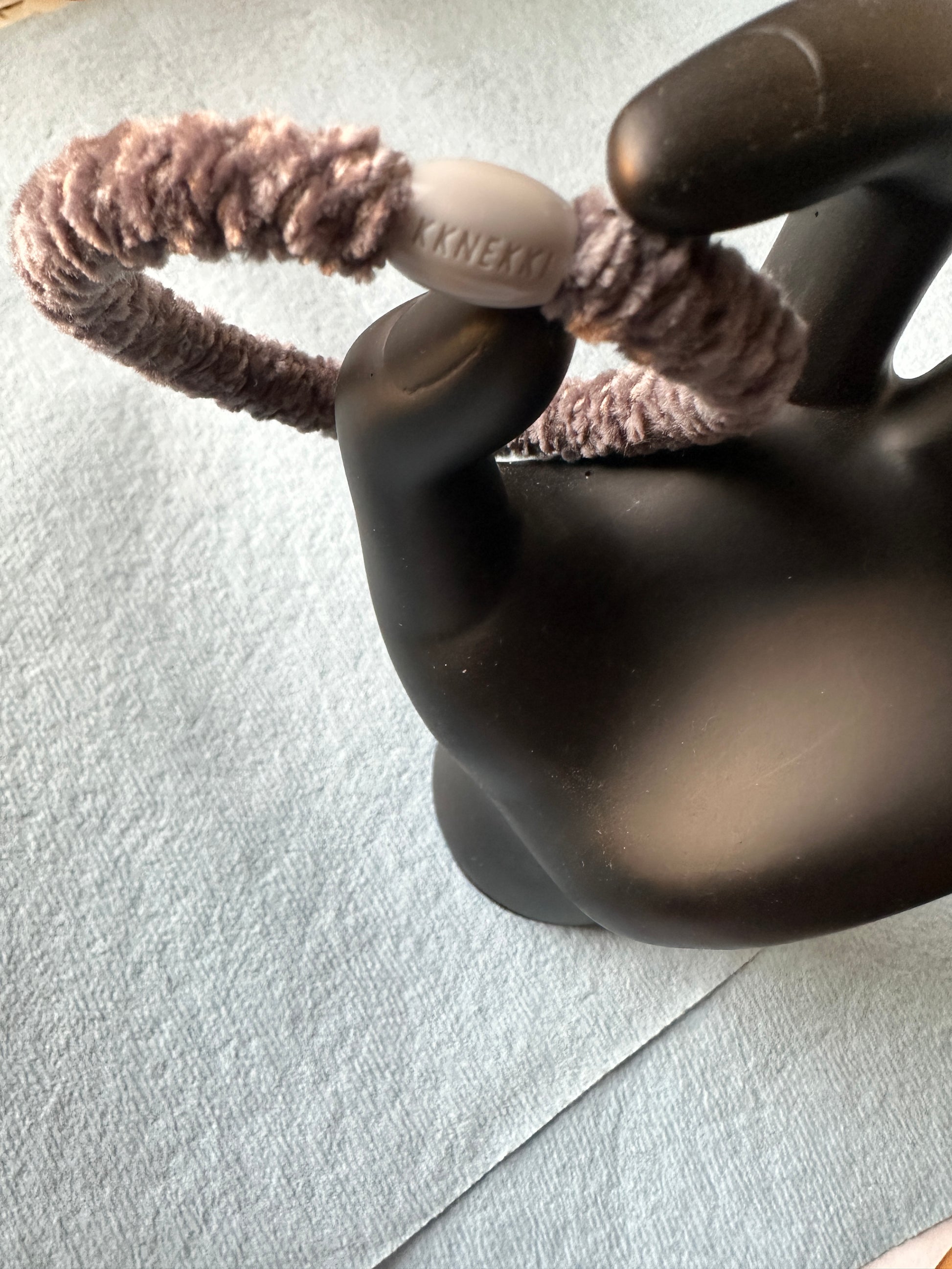 KKNEKKI Coffee hair tie held in a black plastic model hand
