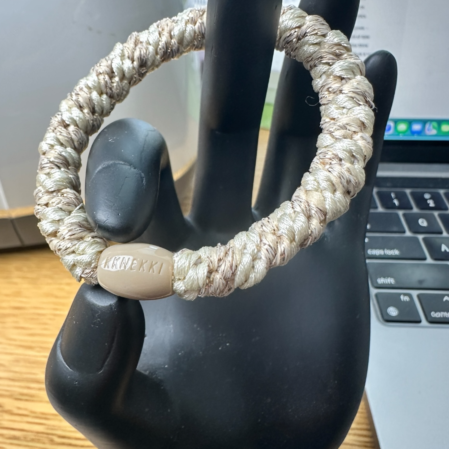 KKNEKKI Cream & Metallic Gold hair elastic on black hand model and office desk shows branded bead