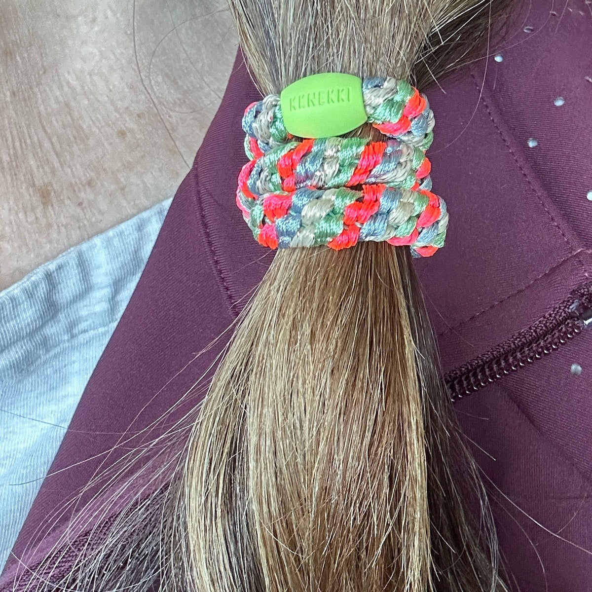 KKNEKKI  Grass Green Pink Neon hair elastic on brunette hair, branded bead visible