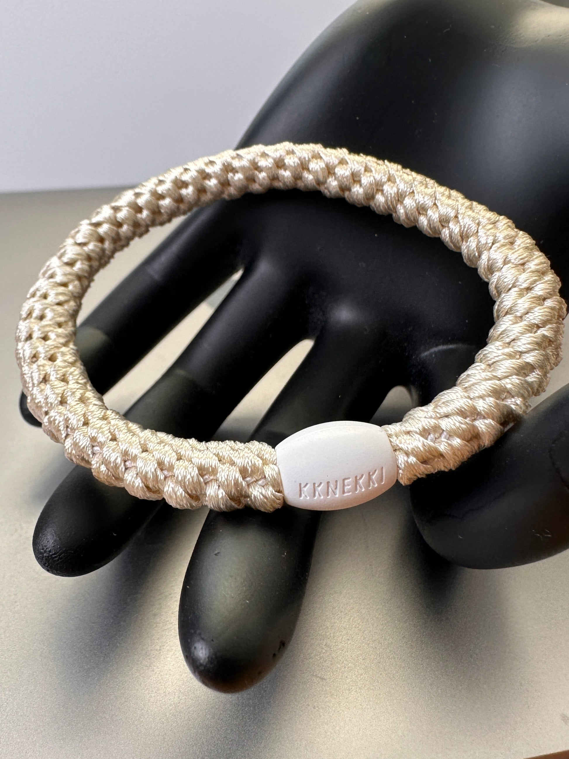 KKNEKKI Ivory hair elastic in model black hand