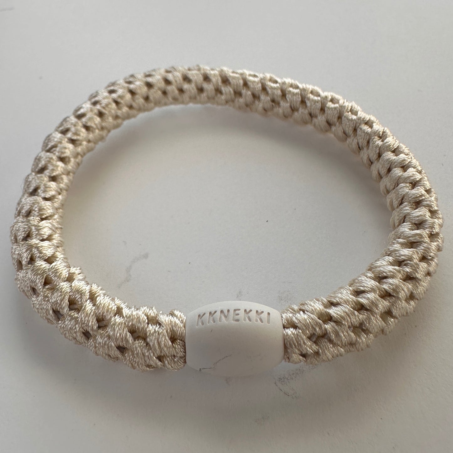 KKNEKKI Ivory hair elastic on white background with branded bead visible