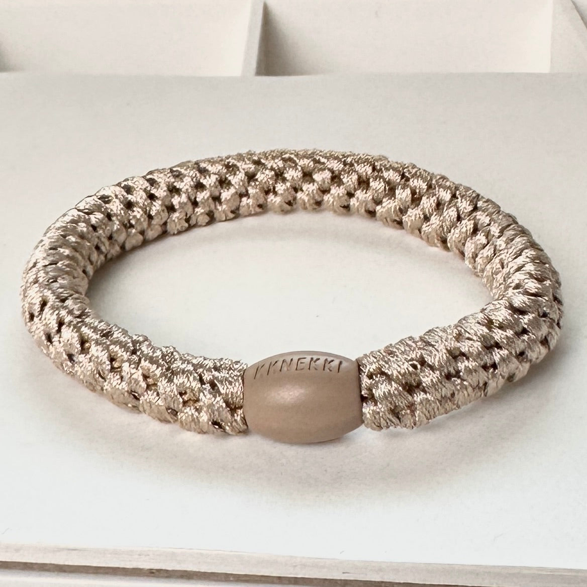 KKNEKKI Light Beige hair elastic showing close up of the branded bead while sitting on white background