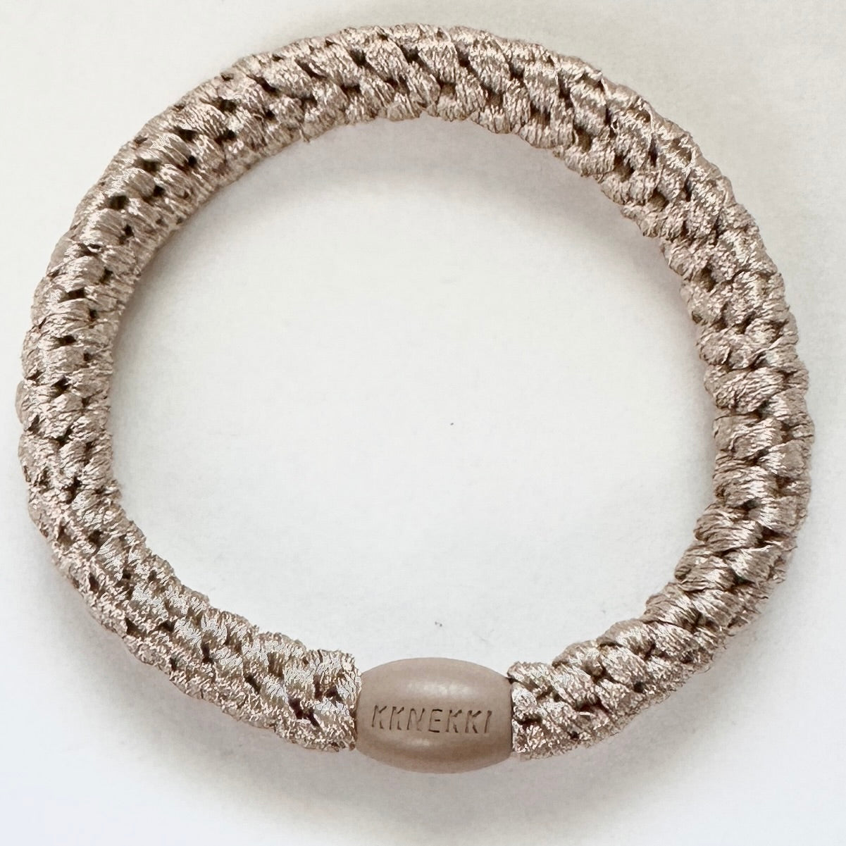 KKNEKKI Light Beige hair elastic viewed from overhead with branded bead visible, sitting on white background