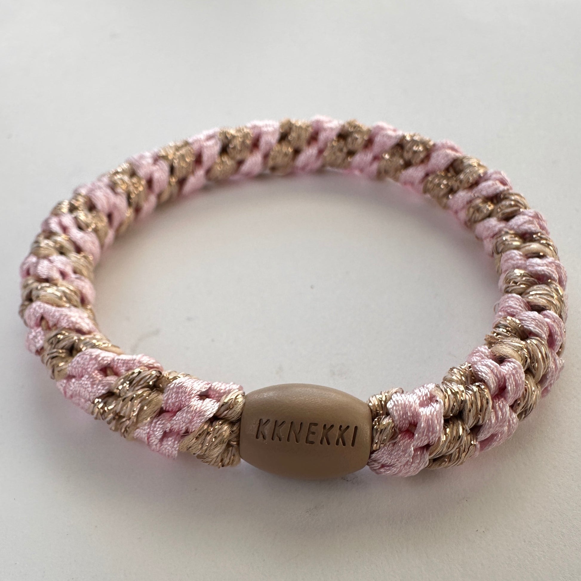 KKNEKKI Light Pink Beige Glitter Stripe hair elastic from side showing close up of strands and branded bead on white background