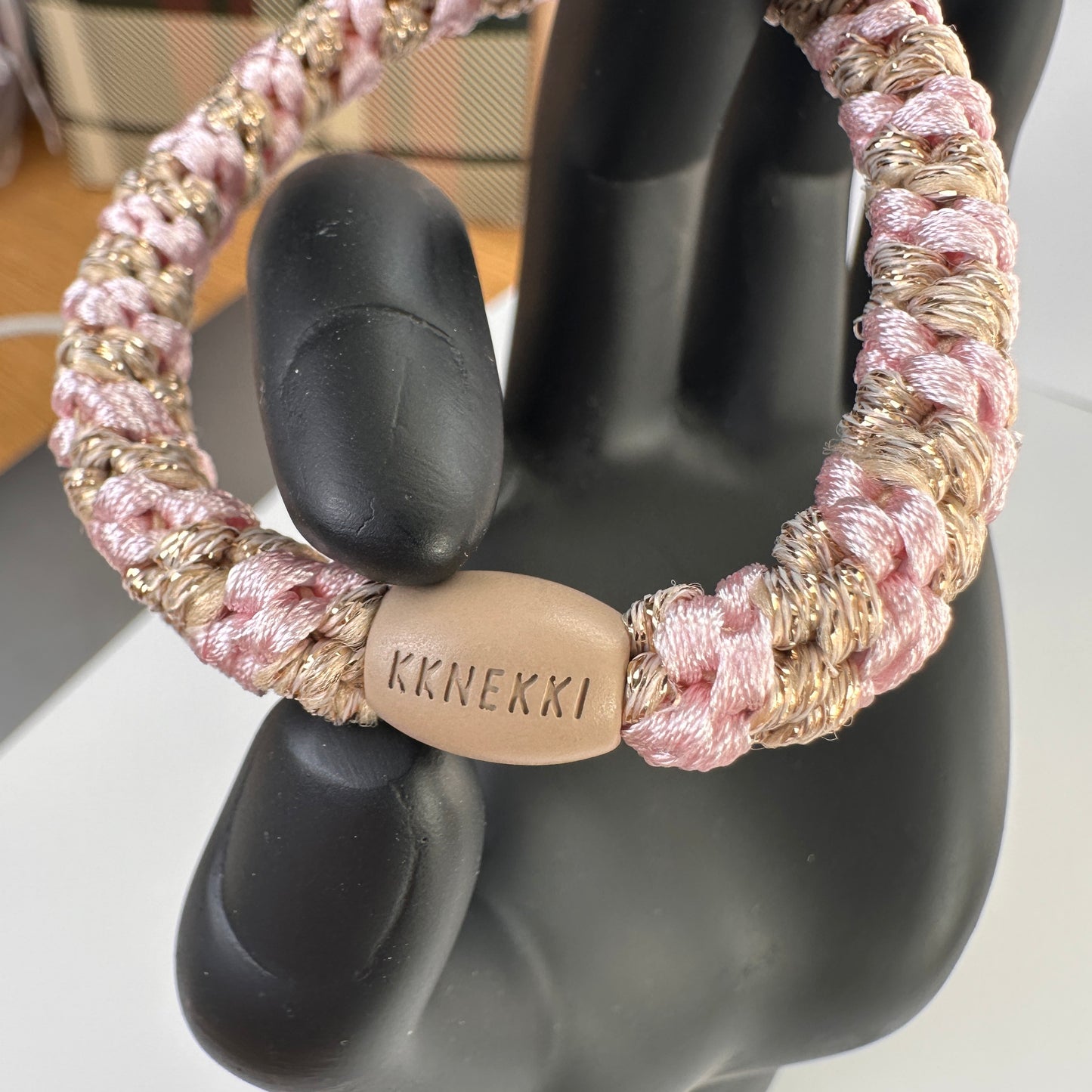 KKNEKKI Light Pink Beige Glitter Stripe hair elastic held by model black hand showing branded bead