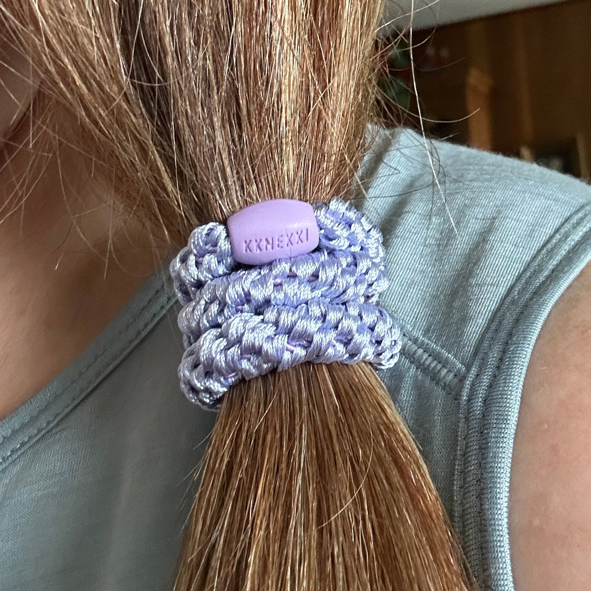 KKNEKKI Lilac hair elastic on brown hair ponytail, branded bead visible