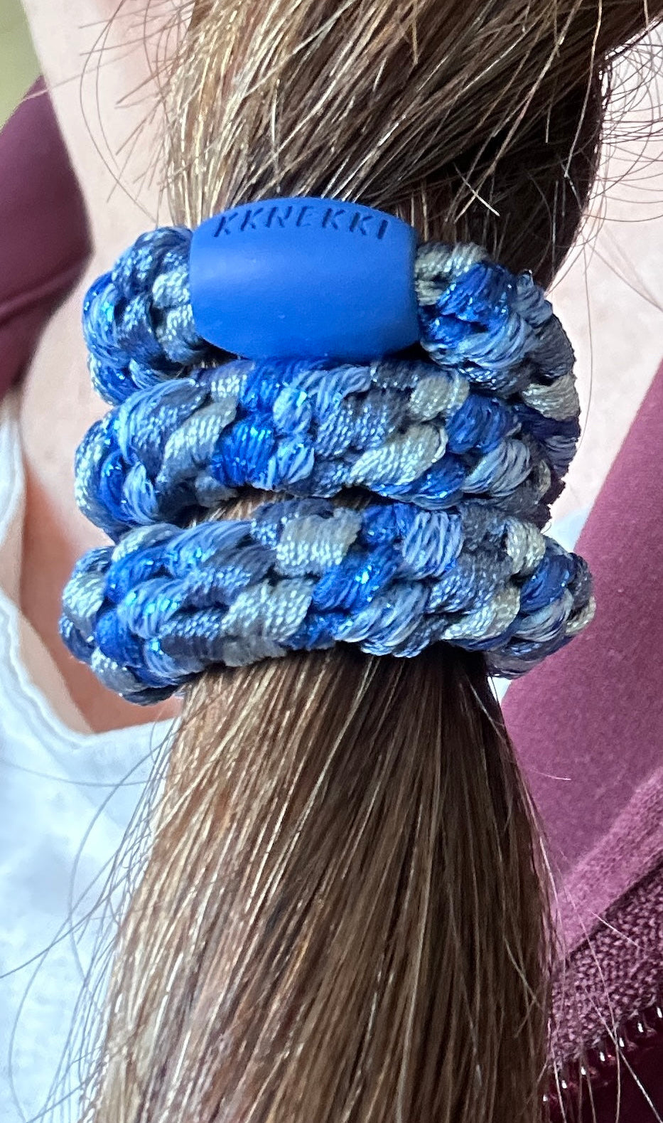 KKNEKKI Mix Blue Tones hair elastics on woman's brunette hair, branded bead visible