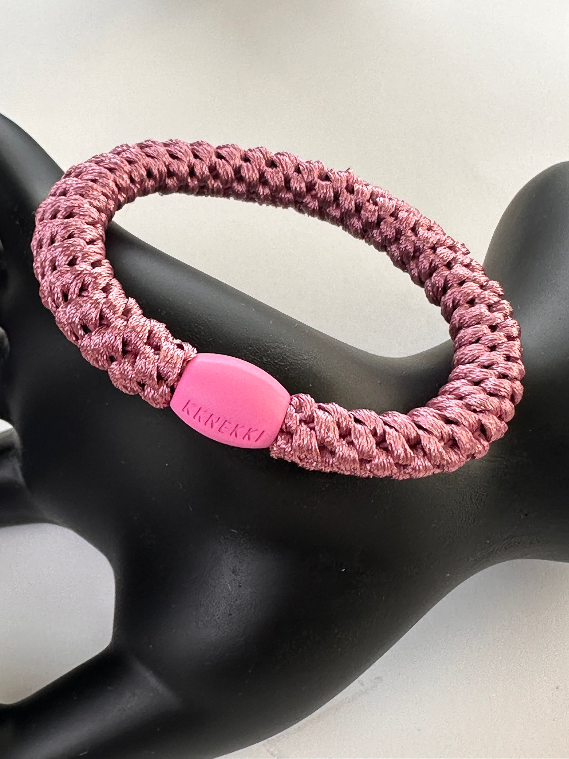 KKNEKKI Old Pink hair elastic on black model hand in front of white background