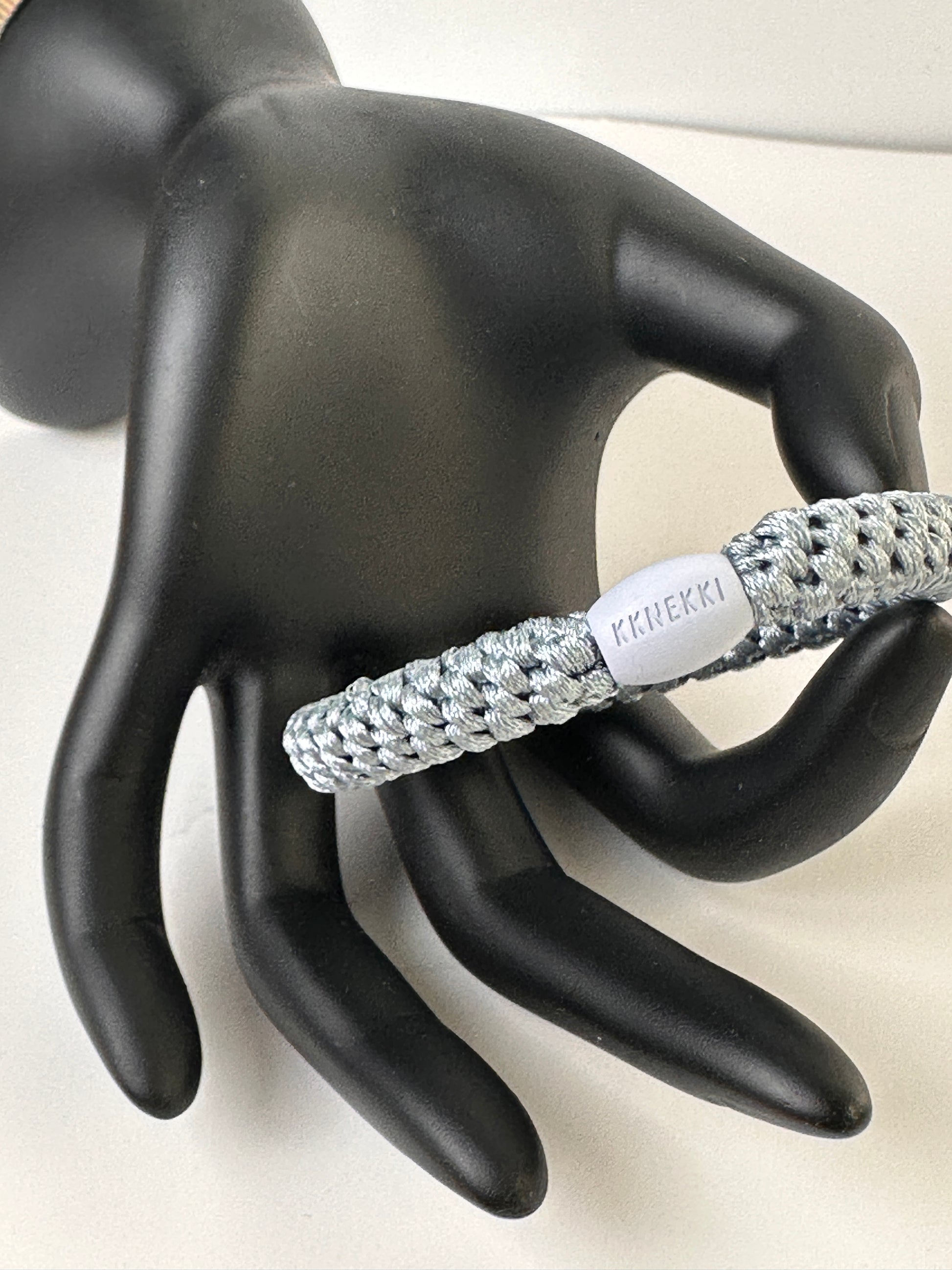 KKNEKKI Sea Blue hair elastic held by black model hand with white background