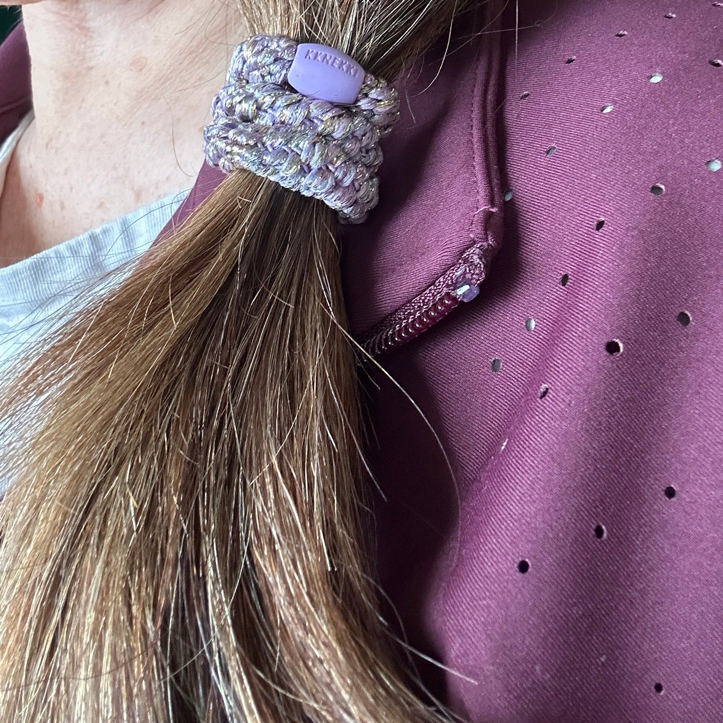 KKNEKKI Unicorn hair elastic shown holding up  a side ponytail in brown hair
