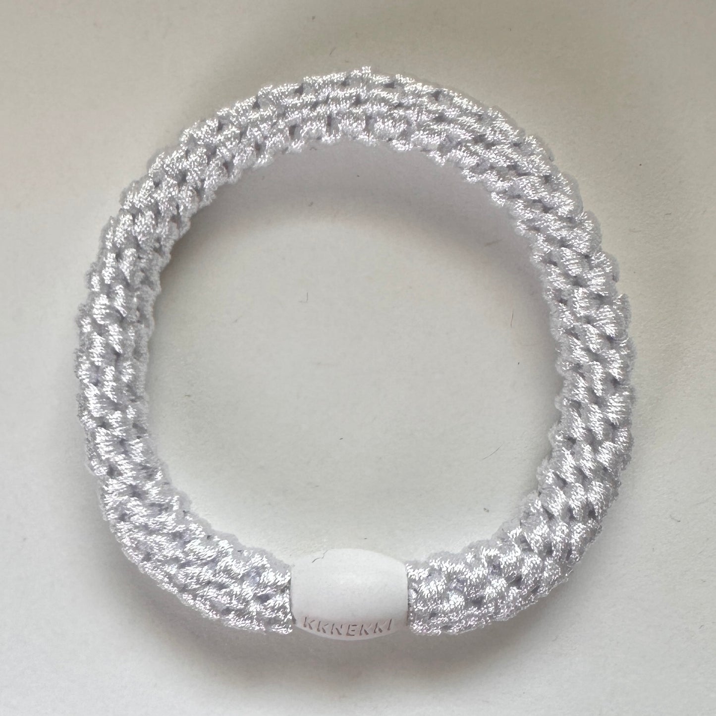 Photo showing KKNEKKI White hair tie with branded bead clearly visible