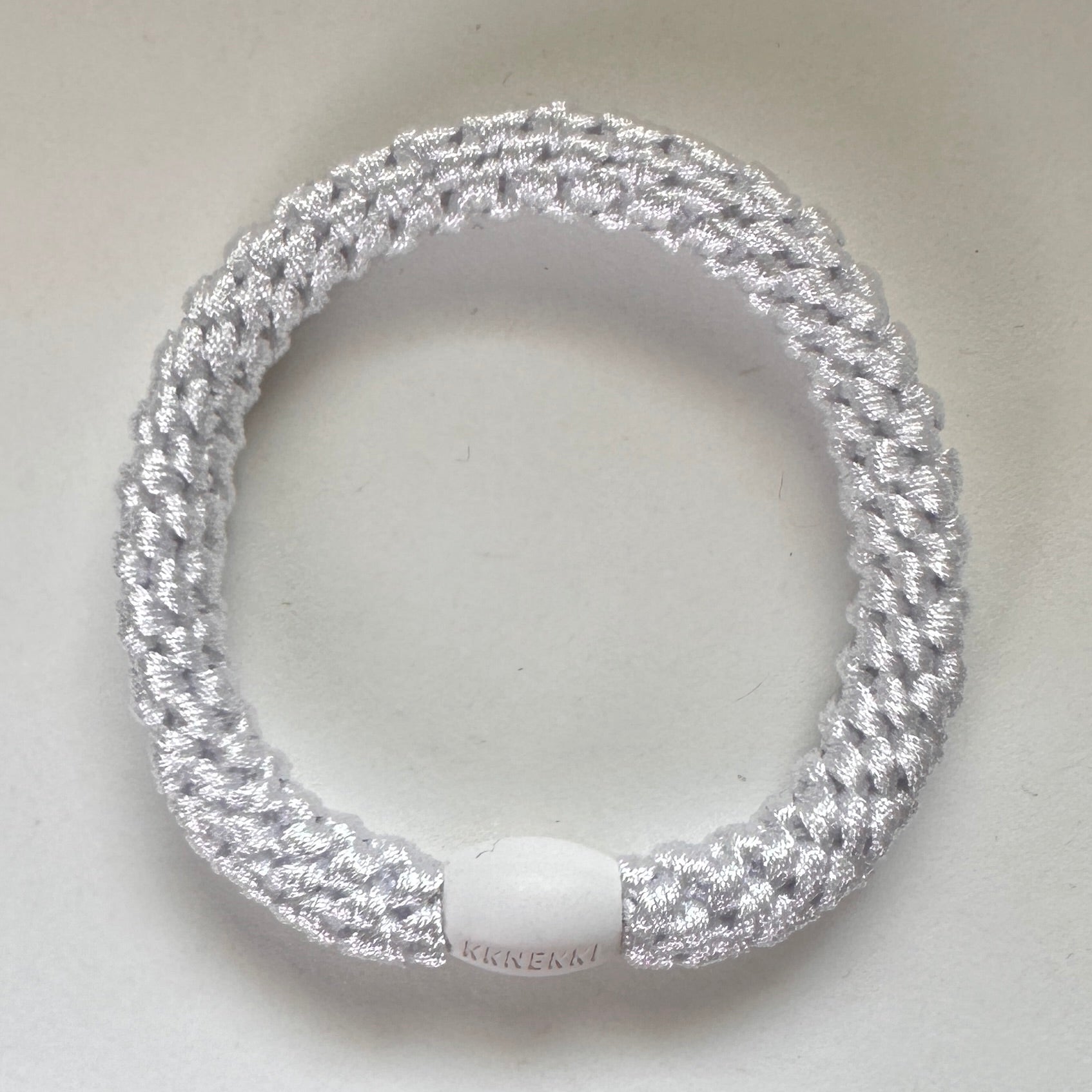 Photo showing KKNEKKI White hair tie with branded bead clearly visible