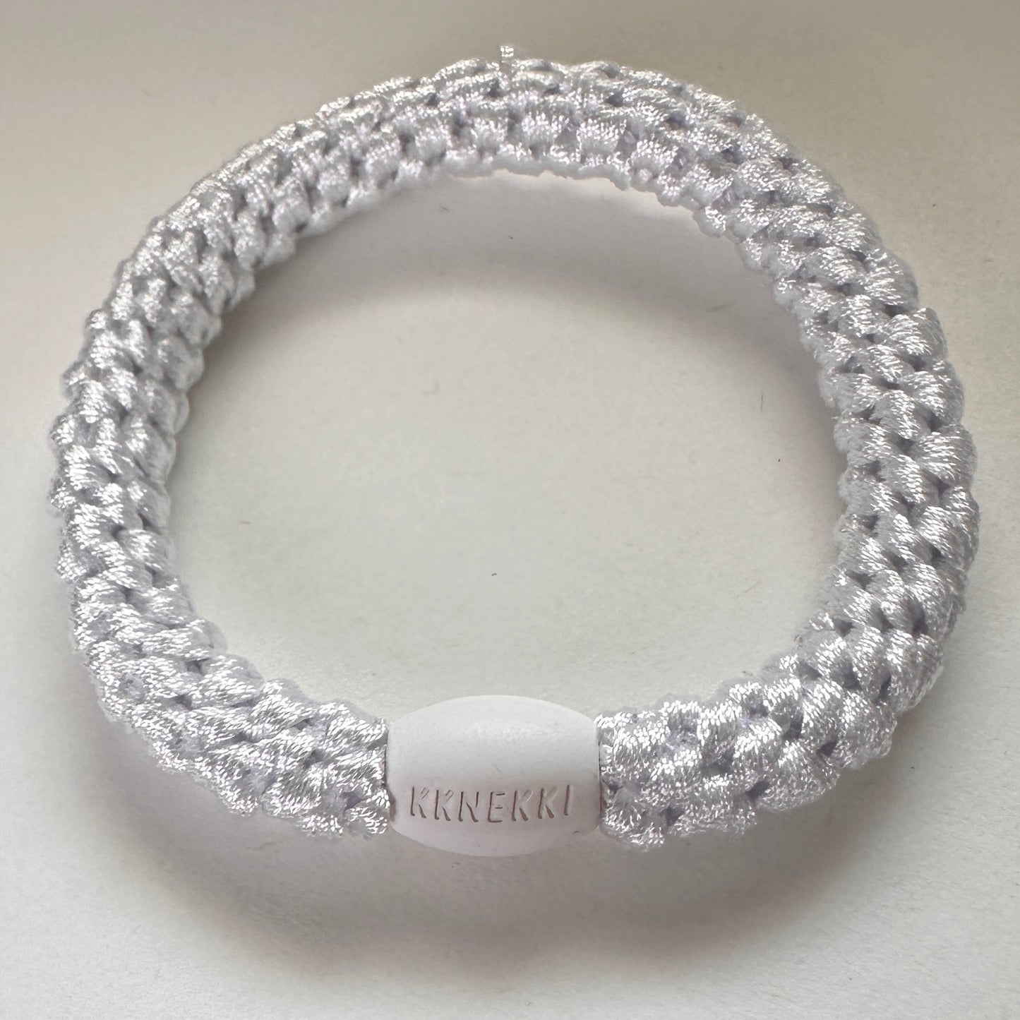 KKNEKKI White hair tie from above on white background close up