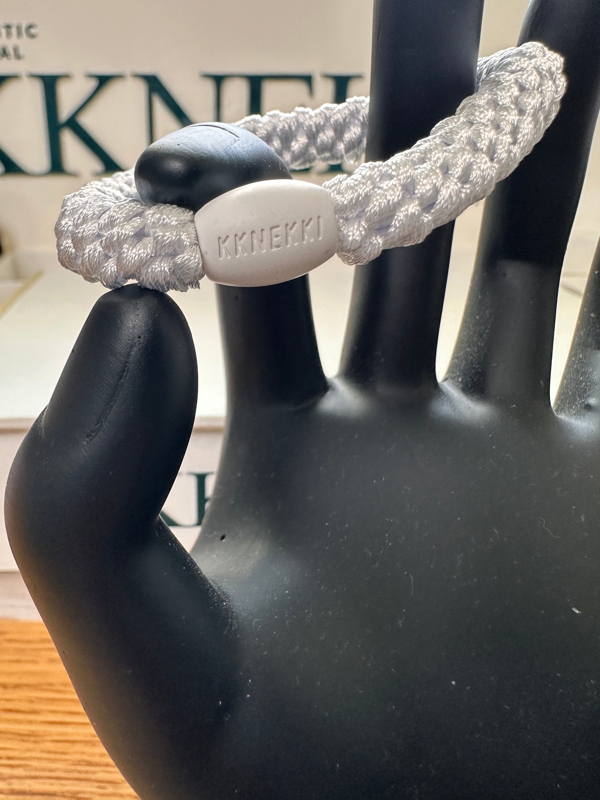 KKNEKKI White hair tie in model hand